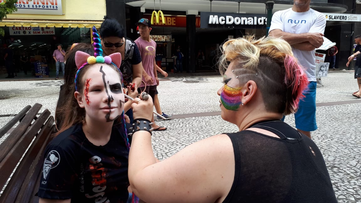 A jovem Gabriela foi uma das primeiras a chegar na caminhada, e foi logo pintando o rosto. Foto: Guilherme Grandi/Gazeta do Povo.