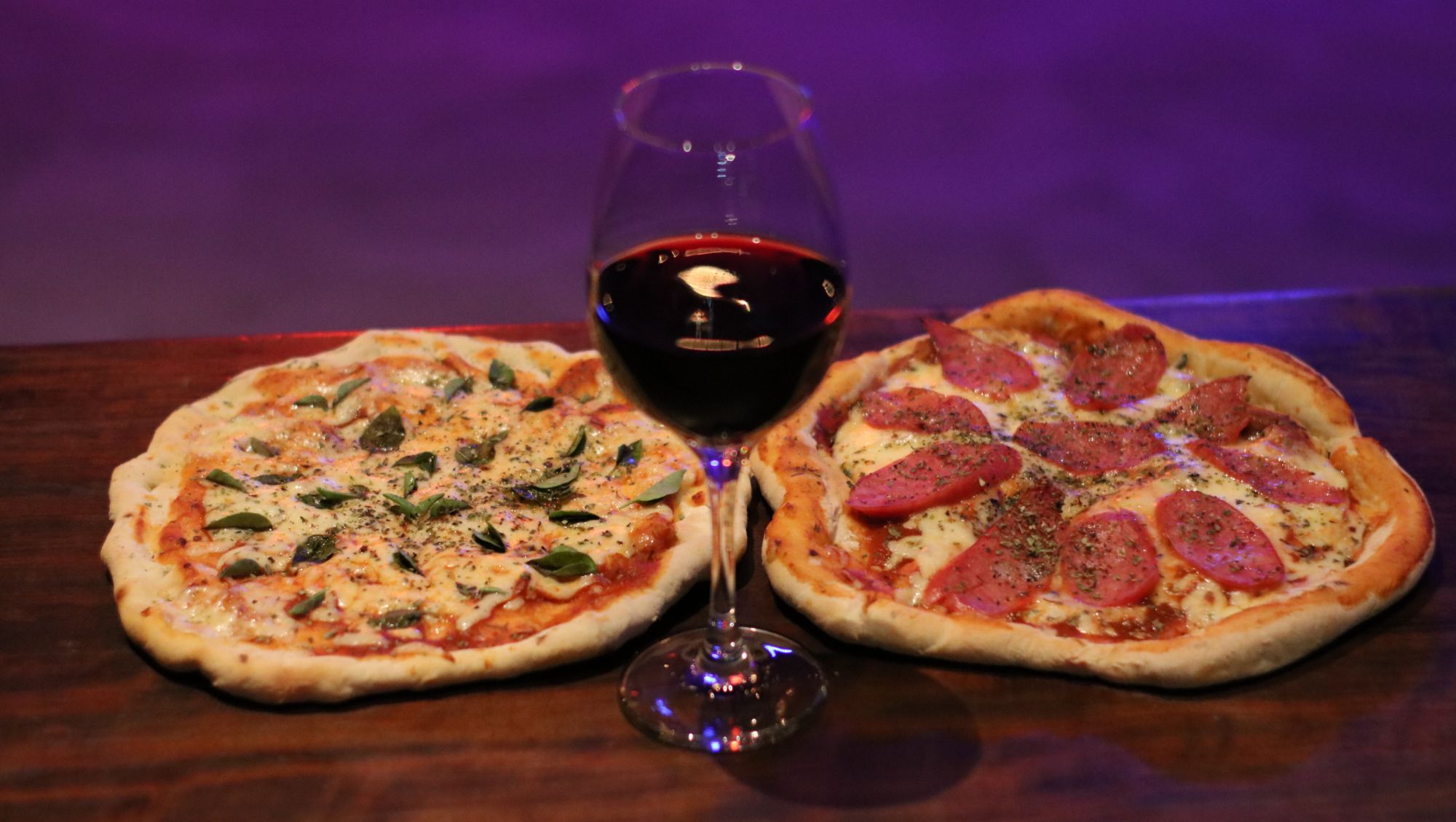 Pizzas do Porta Bar são individuais. Os sabores fixos são margherita (à esquerda) e calabresa. A taça de vinho tinto, não importa o rótulo, sai por R$ 10. Foto: Divulgação