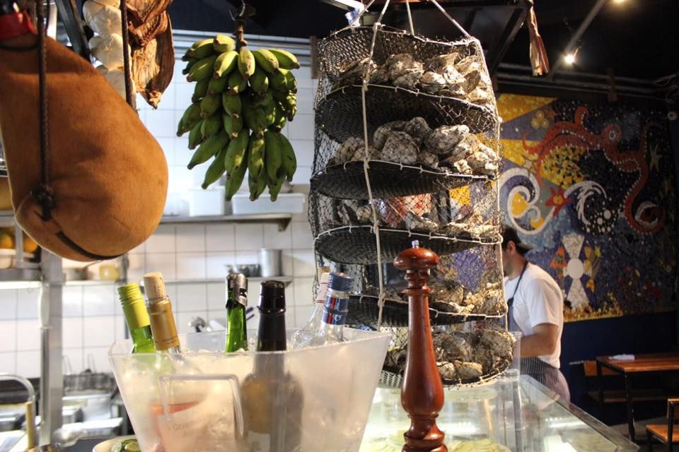 A Ostra Bêbada, no centro de Curitiba, tem vinhos gelando no balcão para servir em taça e também uma carta enxuta para escolher a garrafa. Foto: Reprodução/Facebook